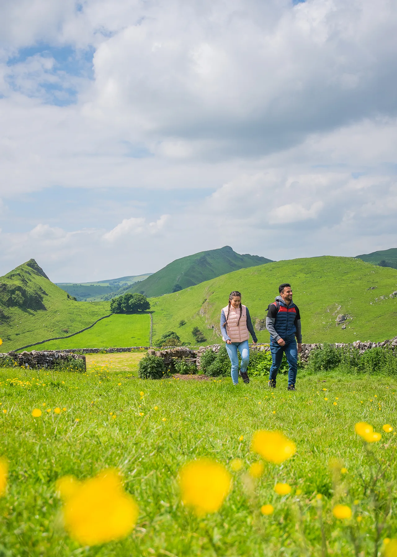 Two people walking through the Peak District hills during Summer